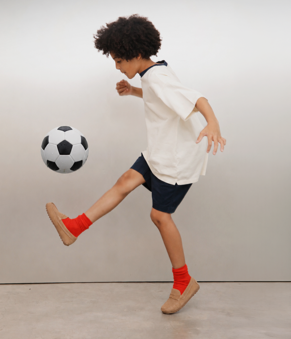 Child playing with a soccer ball against a plain background